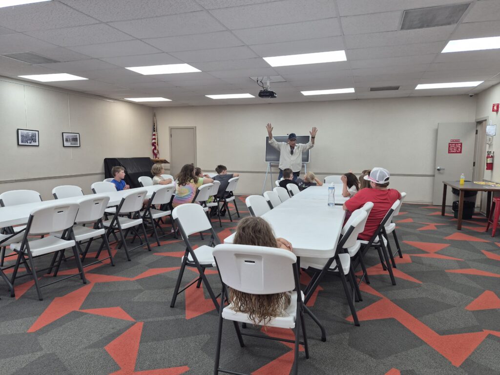 Children sitting in a classroom as District Manager, Danny Barger, presents information (excitedly) on the water cycle).
